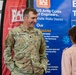 A U.S. Army soldier named Droesch, wearing Army Combat Uniform (ACU) in MultiCam pattern, is engaged in conversation with a civilian at what appears to be a recruitment or outreach event. The setting features banners for the U.S. Army Corps of Engineers, Walla Walla District, describing their missions including hydropower and waterway navigation. The soldier is smiling and appears to be in a friendly, informal discussion.
