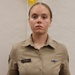 A young person in a khaki military-style uniform stands at attention against a white textured wall. The uniform displays a name tape reading 'COLVIN', a ribbon medal on the right chest, and a patch on the left sleeve. The setting appears to be an official or formal military/JROTC portrait.