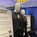This image shows a military uniform display booth, specifically featuring U.S. Space Force dress uniforms on mannequins at what appears to be a recruiting or trade show event. The display includes informational signage describing the design symbolism, new silhouette, and shoulder rank insignia of the Space Force dress uniform. An 'AFOSI RECRUITING' banner is visible in the background.