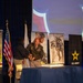 A military ceremony or event appears to be taking place at a joint U.S. Army and Walt Disney Company Veterans Institute event. A uniformed Army soldier and a civilian woman are cutting what appears to be a ceremonial cake on a blue-draped table. The setting includes patriotic banners, U.S. and military flags, and recruitment/promotional imagery.