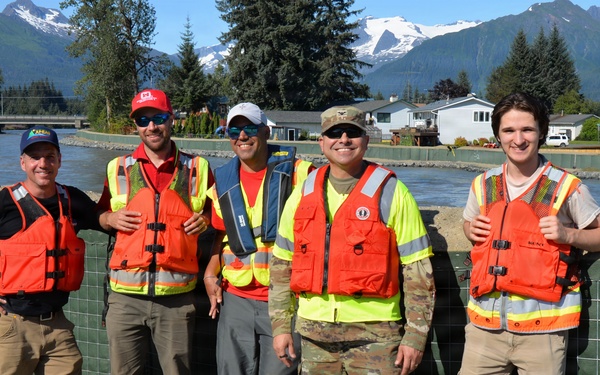Members of the USACE and City and Borough of Juneau team pose for a photo in front of the flood barrier project while performing spot checks during the glacial lake outburst flood