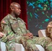 Two U.S. Army soldiers in OCP (Operational Camouflage Pattern) uniforms are seated in white chairs on what appears to be a panel or conference stage. The central figure, identified by name tape as 'OWENS,' wears Airborne and Special Forces patches and is facing left in profile. A second soldier, partially visible on the right with name tape reading 'FERGUSON,' appears to be looking downward.