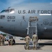 A U.S. Air Force aircraft, tail number 0601, assigned to the 911th Airlift Wing, is shown on a flight line with nose art honoring baseball legend Roberto Clemente. Several airmen in camouflage uniforms are gathered around the front of the aircraft, performing ground operations. The image was taken outdoors under partly cloudy skies on what appears to be a military airfield.