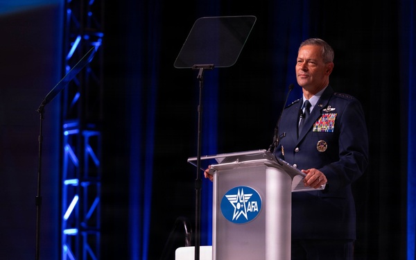 A senior U.S. Air Force officer in dress uniform is delivering a speech at a podium bearing the AFA (Air Force Association) logo. The event appears to be a formal military or defense industry conference held in a large venue with professional stage lighting. The officer displays numerous service ribbons and rank insignia consistent with a general officer.