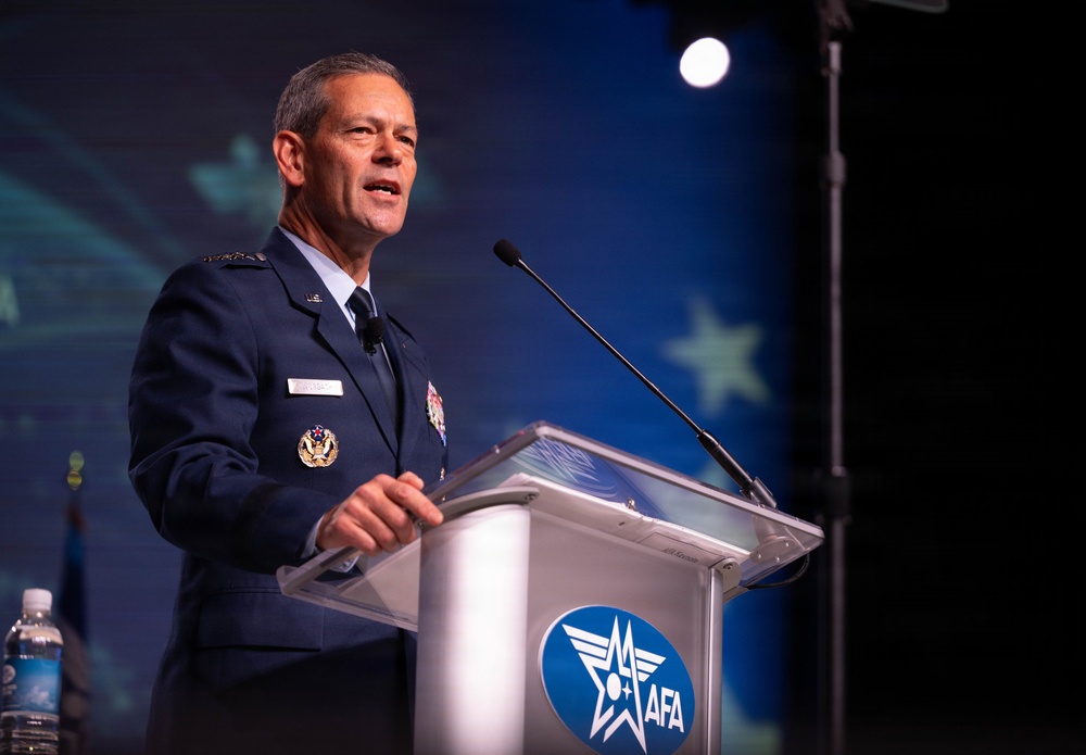 A senior U.S. Air Force officer in dress uniform is delivering a speech at a podium bearing the AFA (Air Force Association) logo. The speaker appears to hold a high-ranking position based on the visible insignia and medals on his uniform. The setting is a formal conference or symposium event.