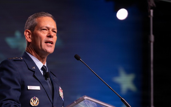 A senior U.S. Air Force officer in dress uniform is delivering a speech at a podium bearing the AFA (Air Force Association) logo. The speaker appears to hold a high-ranking position based on the visible insignia and medals on his uniform. The setting is a formal conference or symposium event.