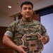A U.S. Marine in MARPAT digital camouflage uniform is holding a wooden shield-shaped award plaque. The plaque is identified as the Marine Forces Reserve Commander's Trophy for the Most Outstanding Multiple Site Performance on the Marine Corps Administrative Analysis Team Inspection (MCAAT). The Marine's name tape reads 'IBARRA' and the branch tape reads 'U.S. MARINES'.