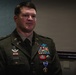 A U.S. Army soldier named Cook, wearing Army Service Uniform (ASU) in olive green, is standing at attention or in a formal posture during what appears to be a military ceremony. He displays numerous decorations including a Purple Heart medal, multiple service ribbons, airborne wings, and special forces insignia. The 'AIRBORNE' tab and unit patches are visible on his left shoulder.