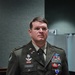 A U.S. Army soldier named Cook stands at attention in Army Green Service Uniform (Class A). He is wearing numerous decorations including what appears to be a Purple Heart medal displayed prominently on his chest. The soldier has Special Forces and Airborne insignia visible, indicating elite military service.