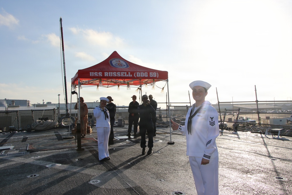 Sailors stand at ease aboard USS Russell (DDG 59) during pier-side ceremony