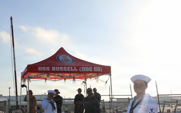 Sailors stand at ease aboard USS Russell (DDG 59) during pier-side ceremony