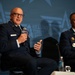 Two military officers in US Air Force dress blue uniforms are seated on a panel stage at an Air &amp; Space Forces Association (AFA) event. The officer on the left is speaking into an AFA-branded microphone while gesturing with his hand. The backdrop prominently displays the AFA logo and 'Air &amp; Space Forces Association' branding.