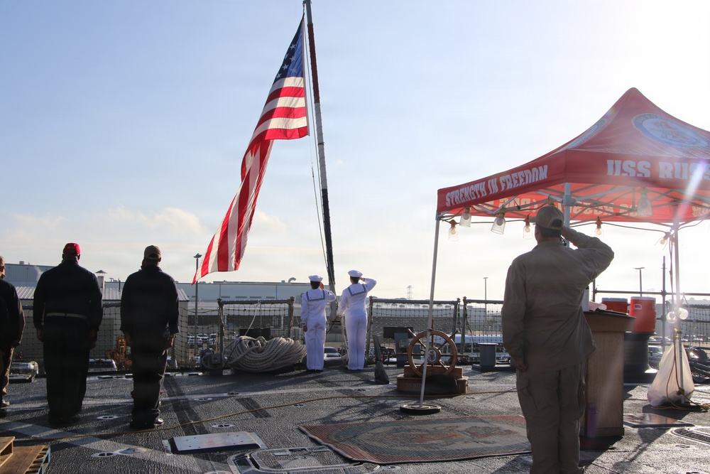Sailors render honors during colors ceremony aboard USS RUSSELL