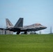 An F-22 Raptor stealth fighter jet is taxiing on a runway, displaying tail markings 'FF' and '192 WG', indicating it belongs to the 192nd Wing of the Virginia Air National Guard based at Langley Air Force Base. The aircraft is photographed from a low angle on a grass-lined airfield under overcast skies. Heat distortion or exhaust is visible behind the aircraft's engines.