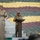 Indian Army leader addresses Yudh Abhyas 2026 formation Two military personnel are present at an outdoor podium, with one officer in Indian Army camouflage uniform speaking at a lectern while a US Army soldier stands nearby. The background features a large arrangement of sandbags in multiple colors — yellow, maroon/red, and green — arranged in horizontal rows, likely forming a decorative or symbolic display. The setting appears to be a formal military ceremony or joint exercise event.
