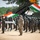 U.S., Indian Armies assemble for Yudh Abhyas 2026 A military parade or joint exercise ceremony featuring soldiers from what appears to be India and the United States, standing in formation on sandy terrain. The Indian tricolor flag is prominently displayed in the background alongside what appears to be a missile launcher system. A small fixed-wing UAV/drone (numbered 4112) is displayed on a stand in the foreground.