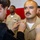 USS Tripoli Chief Pinning A U.S. Navy sailor in khaki service uniform is having insignia or rank devices pinned onto his collar by two individuals during what appears to be a promotion or advancement ceremony. The sailor stands at attention with a composed expression while others in similar uniforms are visible in the background. A red and white backdrop, likely a flag or banner, is visible behind the group.
