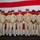 USS Tripoli Chief Pinning A formal group portrait of nine United States Navy personnel in khaki service uniforms standing in front of a large American flag backdrop. The group includes personnel of varying ranks, identifiable by their cover devices, collar insignia, and ribbon/medal arrangements. This appears to be an official military ceremony or recognition event.
