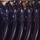 C7F Band Participates in American Sound in Japan The image shows a close-up macro photograph of multiple clothes hangers lined up in a row. The hangers appear to be dark navy or black plastic with a glossy finish, reflecting ambient light as circular bokeh highlights. The shallow depth of field creates a blurred background while keeping the foreground hangers in sharp focus.