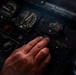 A close-up photograph of an aircraft cockpit control panel, showing a human hand operating controls near labeled switches and gauges. The panel includes markings for 'POWER RUDDEVATORS,' 'AERIAL REFUELING MASTER,' and 'SIGNAL' controls, consistent with a military tanker or transport aircraft. The reference to T.O. 1C-135(K)A-1 and BAC-M93-60-8A suggests this is a KC-135 Stratotanker cockpit.