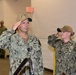 A group of U.S. Navy personnel in NWU Type III (digital camouflage) uniforms are rendering a salute in what appears to be an indoor military facility. The central figure, identified by name tape as 'KILBY,' wears rank insignia consistent with a senior officer and a cap with 'Chief of Naval Operations' text. Multiple sailors are visible saluting in formation, suggesting a formal military ceremony or official visit.