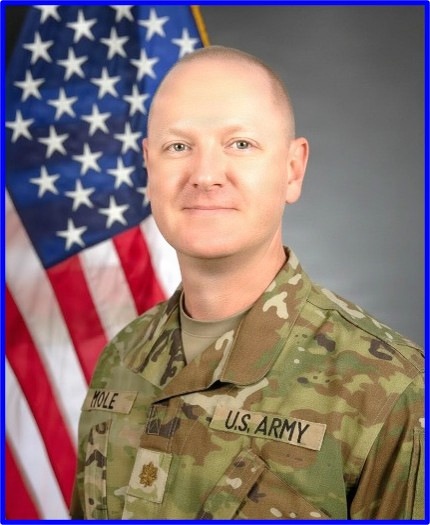 This is a formal U.S. Army official portrait photograph of a male soldier in Army Combat Uniform (ACU/OCP camouflage pattern). The subject is posed in front of an American flag against a gray studio background. His name tape reads 'MOLE' and his branch tape reads 'U.S. ARMY', with a gold oak leaf insignia visible indicating the rank of Major.