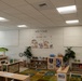 This image shows a well-organized early childhood classroom identified as Room 120. The room features a safari/jungle theme with animal wall decals, colorful educational rugs, and multiple learning stations with wooden furniture. The space appears newly set up or freshly arranged, with no children present.