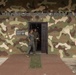 Two military personnel are standing in the doorway of a building belonging to the 'Comandos Aeronavales' (Aeronaval Commandos), part of Panama's Servicio Nacional Aeronaval. The building facade is painted in a woodland camouflage pattern and displays two official unit emblems on either side of the entrance. The individuals appear to be engaged in conversation.