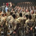A large group of U.S. Army soldiers in OCP (Operational Camouflage Pattern) uniforms are gathered in what appears to be an auditorium or theater setting. Senior officers appear to be addressing or interacting with junior enlisted personnel and lower-ranking soldiers in a semi-circular formation. The setting suggests a post-event gathering, briefing, or meet-and-greet following a formal ceremony or presentation.