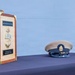 The image shows a formal U.S. Navy Chief Petty Officer promotion ceremony display on a table covered with a dark blue cloth. A decorative wooden keepsake box with brass hardware and a USN anchor emblem is displayed alongside a Chief Petty Officer's combination cover (hat). The plaques on the box reference 'BMC(SW)(EXW) Dylan Jeffers,' 'FY27 Class 133,' and 'September 16, 2026.'