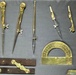 The image shows a collection of antique brass drafting and mathematical instruments displayed on a gray surface. The tools appear to be historical surveying or technical drawing instruments, likely from the 18th or 19th century. Items include various compasses, dividers, a protractor, a set square, and what appear to be parallel rulers or linkage bars.