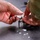 A person wearing military camouflage clothing is handling a white fibrous or powdery substance using a small tool, likely pliers or tweezers, over a dark surface. Small white particles are scattered on the dark surface below. The context suggests a maintenance, cleaning, or material-handling task.