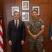 Two individuals pose for a formal photograph in what appears to be an official government or diplomatic office setting. One person is wearing a dark business suit with a red tie and a small lapel pin, while the other is dressed in U.S. Marine Corps digital camouflage (MARPAT) uniform. The setting features both an American flag and a Panamanian flag, suggesting a bilateral diplomatic or military meeting.