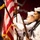 A U.S. Navy color guard is participating in a formal military ceremony. Sailors in dress white uniforms are presenting the American flag and carrying ceremonial rifles. The foreground sailor displays a Petty Officer rating badge on his left sleeve.