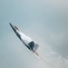 A U.S. Air Force F-22 Raptor stealth fighter jet is captured in a steep near-vertical climb during what appears to be an airshow demonstration. The aircraft is in full afterburner with visible engine flames and a dramatic vapor/condensation cloud forming around the fuselage due to rapid pressure changes. The tail code 'FF' and partial serial number are visible on the aircraft's body.