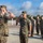 Chief Warrant Officer 2 Joshua J. Krantz’s Promotion Ceremony A group of U.S. Marines in MARPAT woodland camouflage uniforms are engaged in a formal saluting exchange on an outdoor parade deck or tarmac. Two Marines in the foreground are exchanging salutes face-to-face, while four additional Marines stand at attention in the background. The setting appears to be a military base, likely during a formal ceremony or inspection.
