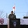 US and Japan Showcase Strong Partnership at Orient Shield 2026 Opening Ceremony A U.S. Army officer wearing a red beret speaks at a podium bearing the 11th Airborne Division ('Arctic Airborne') insignia during an official military ceremony dated September 17, 2026. Three national flags — United States, Japan, and Australia — are displayed in the background, indicating a multinational military event. A banner partially visible behind the speaker references the same date in both English and Japanese.