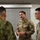 Three military personnel are engaged in conversation in what appears to be an indoor facility. Two U.S. Army soldiers in OCP (Operational Camouflage Pattern) uniforms are speaking with a third individual wearing a different camouflage pattern, likely from a foreign military. The interaction appears to be a professional or liaison meeting between allied forces.