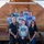 A group of eight people pose for a group photo in front of a wooden structure marked with the number '505'. Most members are wearing tie-dye t-shirts bearing the 'USO Africa' logo, while two individuals in the front row wear black polo shirts also branded with the USO logo. The setting appears to be a military base or forward operating location.