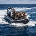 A rigid inflatable boat (RIB) marked 'TUNISIAN NAVY' carries a group of armed military personnel in full tactical gear across open ocean waters. The soldiers are equipped with helmets, body armor, and weapons, suggesting a maritime special operations or boarding exercise. The boat is moving at speed, creating a visible wake behind it.
