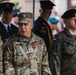 The image shows a multinational military gathering featuring U.S. Army and Polish Army personnel in uniform. A central U.S. Army officer with the name tape 'DEMONTIGNY' and a one-star general insignia is prominently visible. The setting appears to be a formal military ceremony or official event.