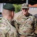 Two military personnel are engaged in conversation outdoors, likely at a military installation or exercise area. The soldier facing the camera wears U.S. Army OCP (Operational Camouflage Pattern) uniform with the name tape 'KING' and a Lieutenant Colonel oak leaf insignia. The other individual, seen from behind, wears a green beret suggesting possible special forces or allied military affiliation.