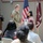 BACH Conducts Commanders Monthly Awards Ceremony A U.S. Army officer in camouflage uniform is presenting a certificate or award to a civilian woman during a formal military ceremony. A second uniformed soldier stands at a podium in the background. An audience of both military personnel and civilians is seated in the foreground.