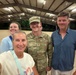 A group of four people posing for a selfie inside what appears to be an open-air covered arena or pavilion at night. One individual is wearing a U.S. Army uniform with the name tape 'RODERICK' and an OCP (Operational Camouflage Pattern) uniform. The group appears to be in a casual, celebratory gathering.