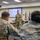 Lt. Gen. Stanton speaks at DISA headquarters A U.S. Army officer in OCP (Operational Camouflage Pattern) uniform is presenting to a group of seated military personnel in what appears to be a briefing or classroom setting. A projection screen behind the speaker displays a slide referencing 'LTG Paul T. Stanton' and what appear to be two military insignia seals. The setting suggests a formal military briefing or training event.