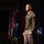 Lt. Gen. Stanton speaks at DAFITC A senior U.S. Army officer in dress uniform stands on a stage, appearing to address an audience at a formal military or defense-related event. He is wearing an olive green Army Service Uniform with visible rank insignia, unit patches, and service ribbons. Multiple flags, including the U.S. flag, are displayed in the background.