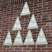 A brick wall displays seven green triangular memorial plaques from 'triangleoftribute.com', each bearing a silhouette profile and honoring American soldiers killed in action on 17 September 1944. The soldiers were members of the 504th Parachute Infantry Regiment, 82nd Airborne Division. Small American flags and flowers have been placed at the base of the wall as a tribute.