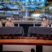 A military panel discussion is taking place on a stage, featuring four U.S. Army soldiers seated at two tables draped in dark cloth. The event is associated with the 3rd SBCT, 4th Infantry Division 'Arrowhead,' with COL Nick Sinclair and CSM Ryan Dilling listed as participants, moderated by COL Dan Cannon, Commander of the 6th CA Brigade. A large projection screen behind them displays the panel information alongside images of military tanks.