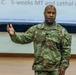 A U.S. Army Colonel named Parker is delivering a presentation or briefing in what appears to be a military training or conference room. He is wearing the Army Combat Uniform (ACU) in OCP (Operational Camouflage Pattern) and gesturing with his right hand while speaking. A projected slide behind him references '5-weeks MT and Lethal combi...' suggesting a training or readiness briefing.