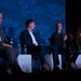 Four panelists are seated on a stage at an AFA (Air &amp; Space Forces Association) event, engaged in a panel discussion. One panelist is actively speaking into a microphone while the others listen. The backdrop prominently displays the AFA logo and branding in blue tones.